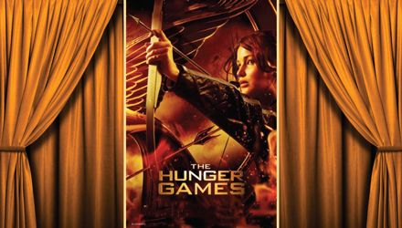 Movie Poster of 'The Hunger Games' framed by a gold colored velvet curtain.